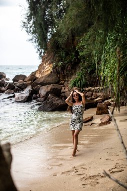 Dalgalar yavaşça ayaklarını öperken bir kadın güzel kumlu sahil boyunca huzurlu ve huzurlu bir yürüyüşün tadını çıkarıyor.