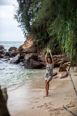 Dalgalar yavaşça ayaklarını öperken bir kadın güzel kumlu sahil boyunca huzurlu ve huzurlu bir yürüyüşün tadını çıkarıyor.