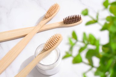 Birçok bambu diş fırçası ve kabın içinde beyaz mineral diş tozu - kaolin tozu veya beyaz mermer arka planda beyazlatan diş beyazlatıcı için kabartma tozu.