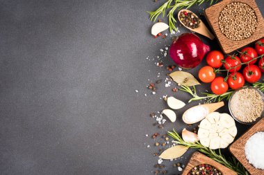 Fotokopi alanı olan yiyecek arka planı - çeşitli baharatlar, otlar, ahşap kaselerdeki baharatlar ve koyu beton arka plandaki sebzeler. Yukarıya bak