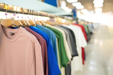 İkinci el dükkanında ya da ikinci el mağazasında askılarda asılı giysiler. Moda mağazasında yeni moda koleksiyonu. Kıyafet kiralama. Giysiler kopya alanı ile bulanık depolama arka planına karşı dururlar