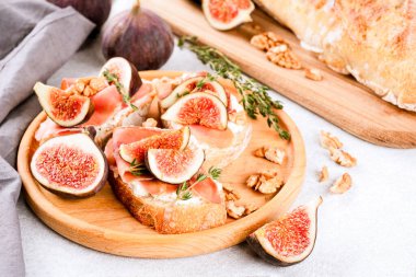 Çiğ incir, krem peynir, prosciutto, ceviz ve bal ile bembeyaz beton masa. Sağlıklı kahvaltı tarifi. İtalyan antipasti yemeği. Seçici odak