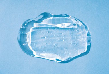 Kozmetik jel dokusu. Mavi arkaplanda saydam jel lekesi var. Doğal cilt bakımı ürünü. Antiseptik ve dezenfektan jel dokusu