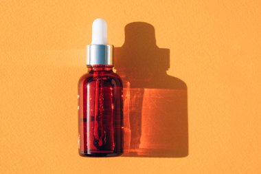  Turuncu zemin üzerinde yüz serumu olan kırmızı cam damlatıcı şişesi fotokopi alanı, meyve özlü güzellik ürünleri. C vitamini ile doğal yüz yağları.