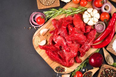 Baharatlı çiğ et ya da kuzu eti, otlar ve sebzeler koyu beton arka planda fotokopi alanı ile birlikte. Pişirme güveci, azu veya diğer ana et yemekleri için organik dana eti