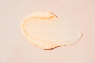 İpeksi kozmetik krem dokusu. Pastel bej arka planda krem ya da vücut yağı lekesi. Cilt ürünleri lekesi