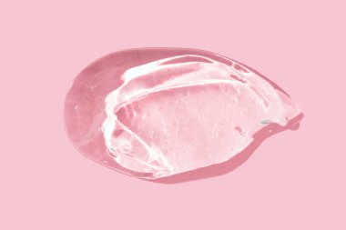 Kozmetik jel dokusu. Pembe arka planda şeffaf jel lekesi. Doğal cilt bakımı ürünü. Antiseptik ve dezenfektan jel dokusu