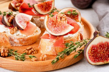 İncirli, krem peynirli, jambonlu, cevizli ve kekikli tostun yakın görüntüsü. Hızlı, sağlıklı bir kahvaltı fikri. İtalyan mutfağı. Seçici odak