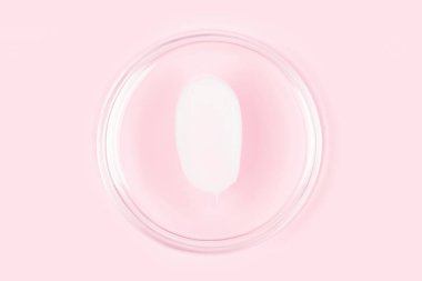 White cream smear. Silky texture of beauty product - face or eye cream, body lotion. White cream smudge over pastel pink background 