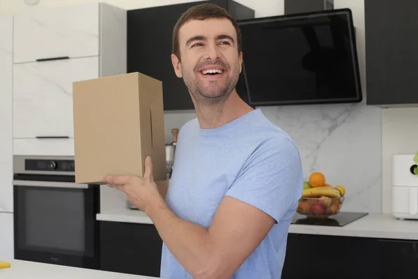 stock image portrait of handsome young man with cardboard box at kitchen