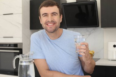 Mutfakta bir bardak temiz suyla yakışıklı bir gencin portresi.