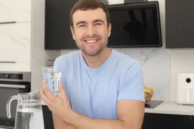 Mutfakta bir bardak temiz suyla yakışıklı bir gencin portresi.