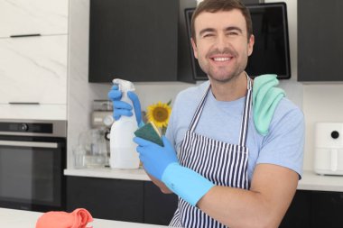 Mutfaktaki temizlik spreyi ve malzemelerle yakışıklı bir gencin portresi.