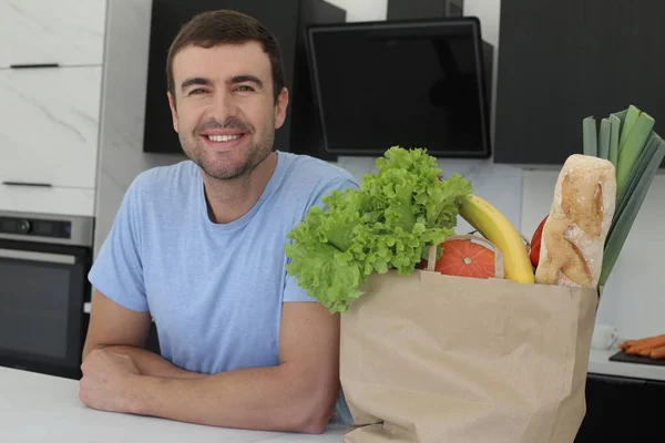 台所に新鮮な野菜の袋を持ったハンサムな青年の肖像画 — ストック写真