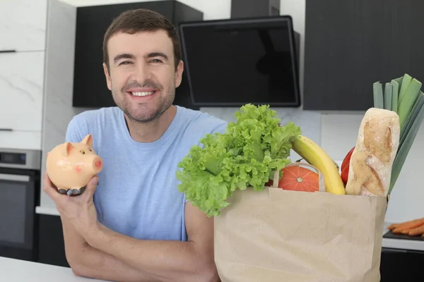 キッチンで貯金箱を持っている新鮮な野菜の袋とハンサムな若い男の肖像画 — ストック写真
