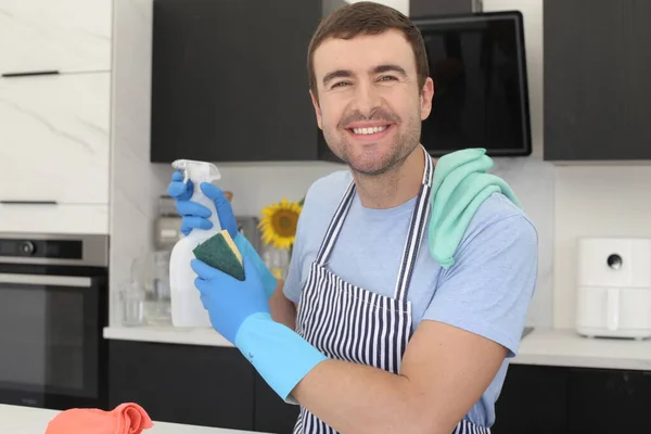 台所でスプレーや消耗品を掃除しているハンサムな若い男の肖像画 — ストック写真