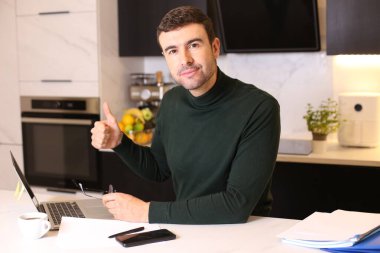 Bilgisayarlı yakışıklı bir gencin portresi mutfaktan çalışıyor.