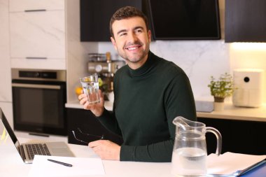 Mutfakta çalışırken su içen yakışıklı bir gencin portresi.