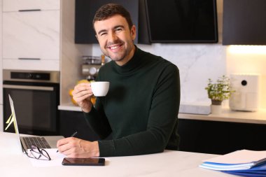 Mutfaktan çalışan bir fincan kahveyle yakışıklı genç adamın portresi.