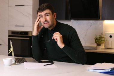 Bilgisayarlı yakışıklı bir gencin portresi mutfaktan çalışıyor.