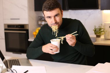 Mutfakta çalışırken erişte yiyen yakışıklı bir gencin portresi.