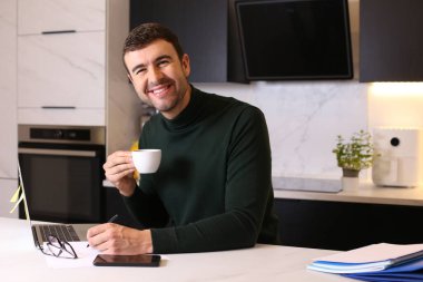 Mutfaktan çalışan bir fincan kahveyle yakışıklı genç adamın portresi.