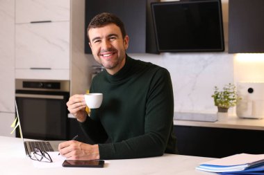 Mutfaktan çalışan bir fincan kahveyle yakışıklı genç adamın portresi.