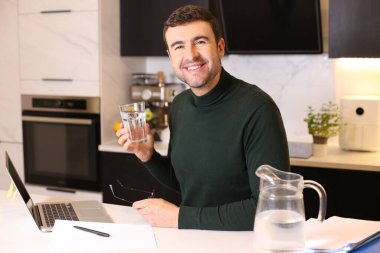 Mutfakta çalışırken su içen yakışıklı bir gencin portresi.