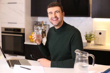 Mutfakta çalışırken su içen yakışıklı bir gencin portresi.