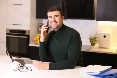 Mutfakta çalışırken telefonla konuşan yakışıklı bir gencin portresi.