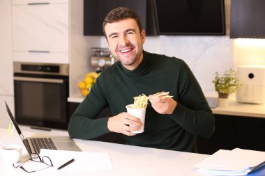 Mutfakta çalışırken erişte yiyen yakışıklı bir gencin portresi.