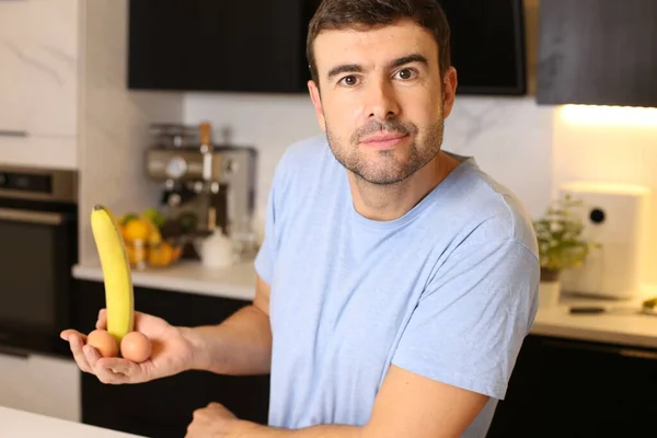 Portrét Pohledného Mladého Muže Držícího Banán Kuchyni — Stock fotografie