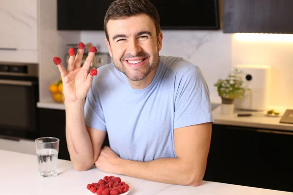 stock image portrait of handsome young man with raspberries at kitchen