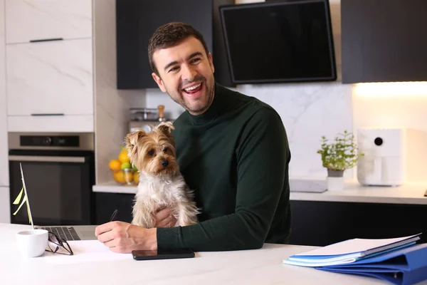 stock image portrait of handsome young man with his cute little dog at kitchen