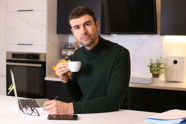 stock image portrait of handsome young man with cup of coffee working from home at kitchen