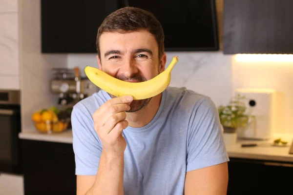 Portrét Pohledného Mladého Muže Držícího Banán Kuchyni — Stock fotografie