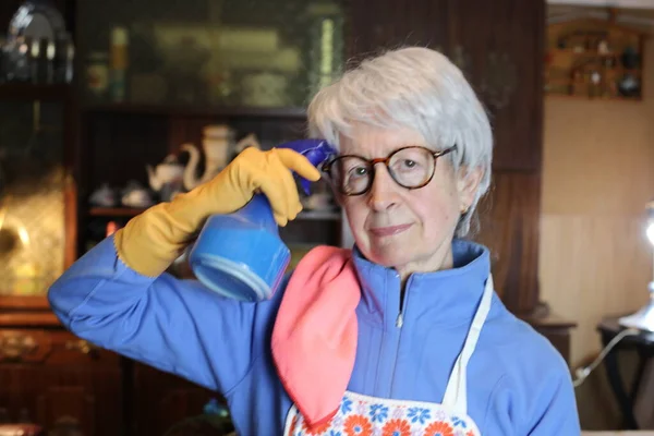 close-up portrait of mature woman in apron cleaning her home