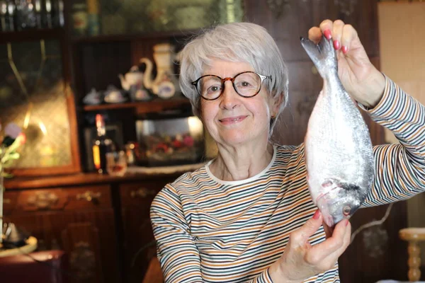 close-up portrait of mature woman with raw fish at home
