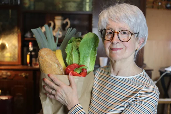 家庭での食料品の袋を持つ成熟した女性のクローズアップ肖像画 — ストック写真
