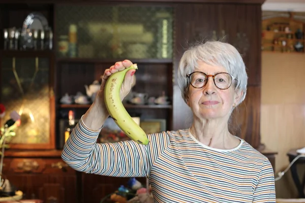 close-up portrait of mature woman with banana at home