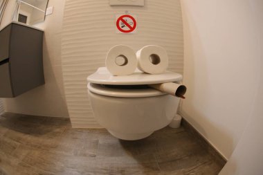 wide angle shot of smoking toilet face made with paper rolls, comedy concept