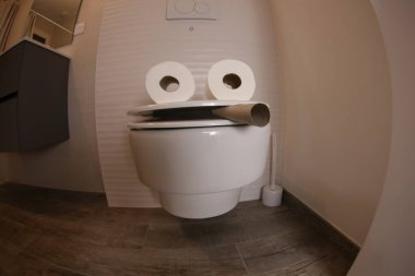 wide angle shot of smoking toilet face made with paper rolls, comedy concept