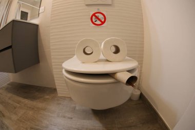 wide angle shot of smoking toilet face made with paper rolls, comedy concept