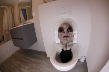 wide angle shot of alien head sticking out of toilet, comedy concept