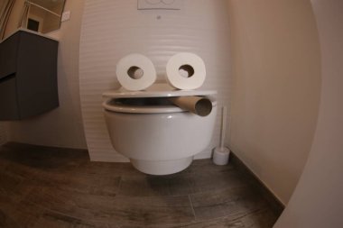 wide angle shot of smoking toilet face made with paper rolls, comedy concept