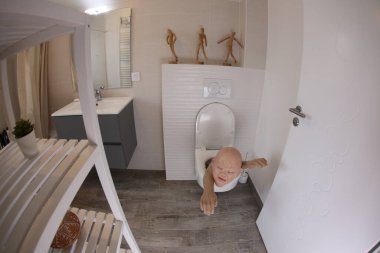 wide angle shot of person sticking out of toilet, comedy concept