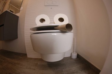 wide angle shot of smoking toilet face made with paper rolls, comedy concept