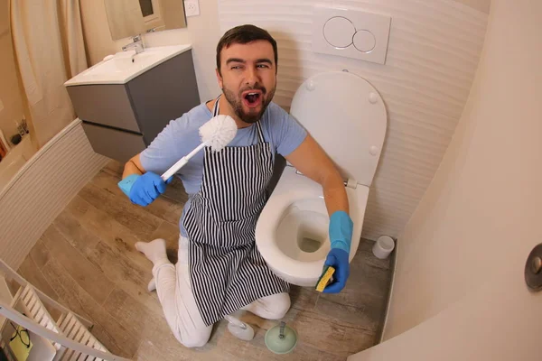 wide angle shot of young man cleaning toilet