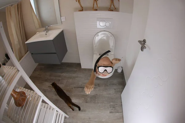 wide angle shot of person with snorkel and diving mask sticking out of toilet, comedy concept