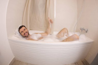 wide angle shot of handsome young man having fun in bath